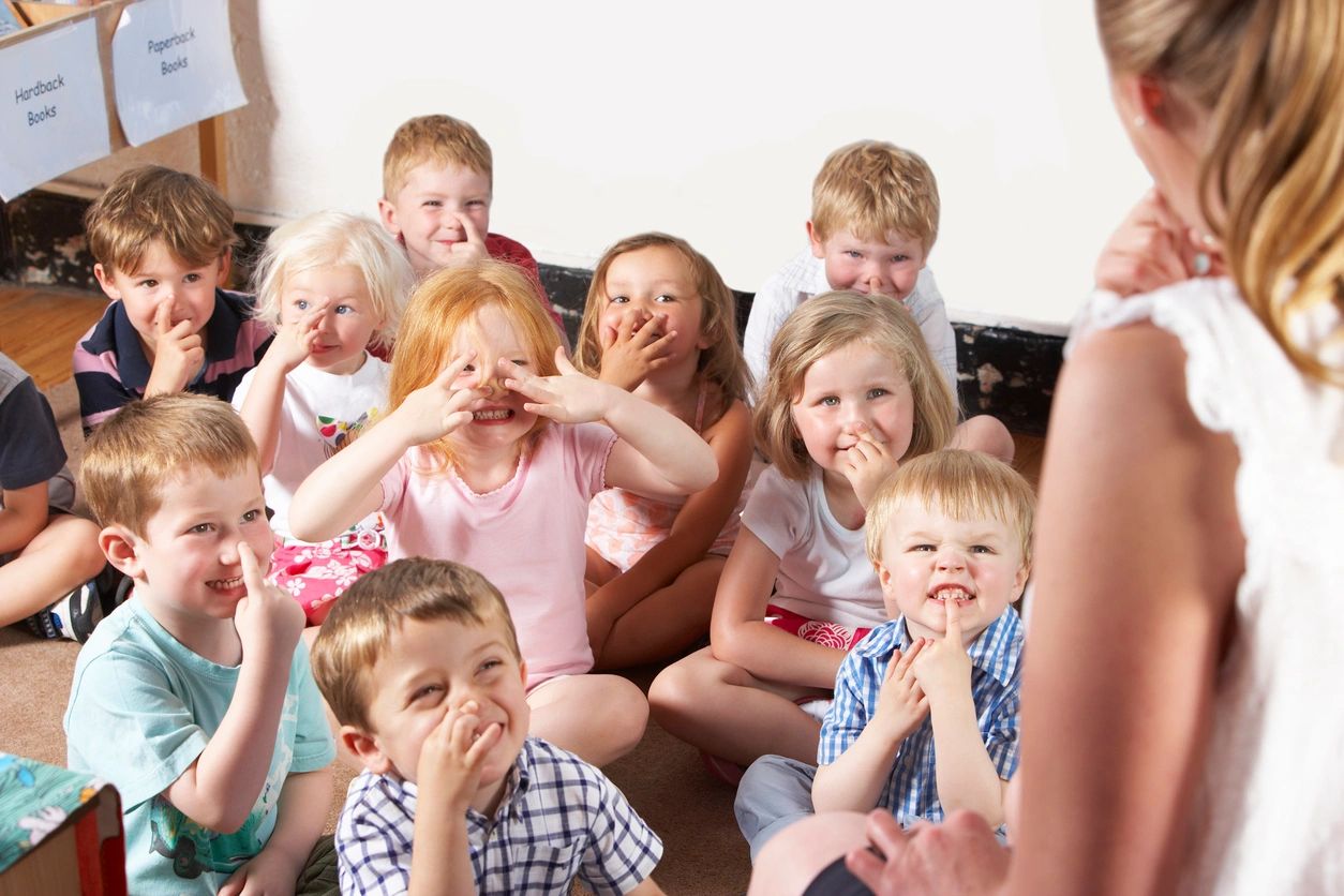 A group of children sitting in front of an adult.