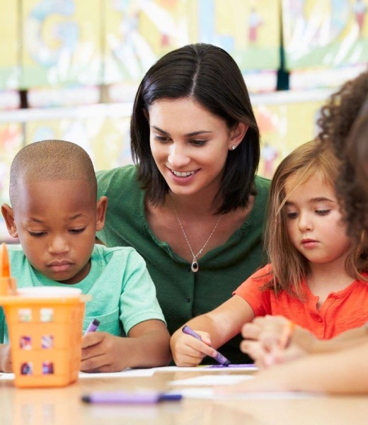 A woman is helping children with their writing.