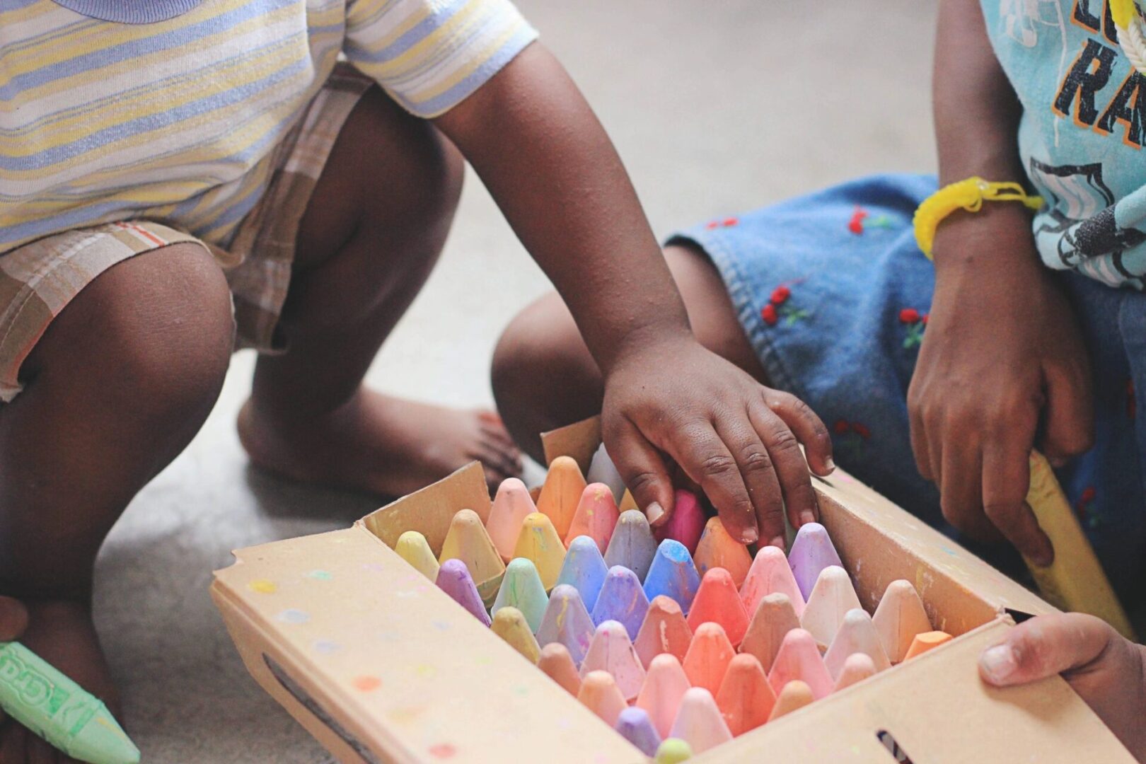 A child playing with colored chalk in a box.